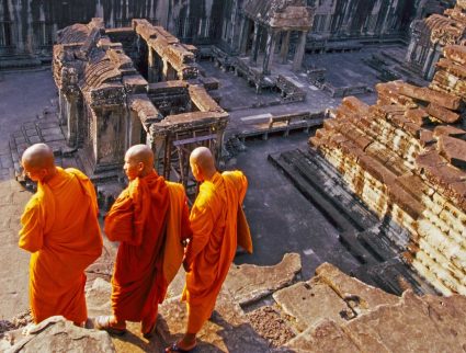 Three monks overlook Angkor Wat, Cambodia with GeoEx