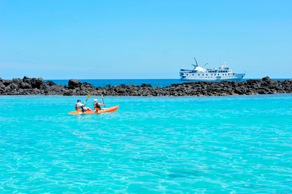 Kayakers on the water with La Pinta ship in the distance, Galapagos, Ecuador