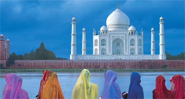 Colorful women standing in front of the Taj Mahal in India.