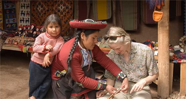 Mother and daughter showing tourist how to weave in Peru.