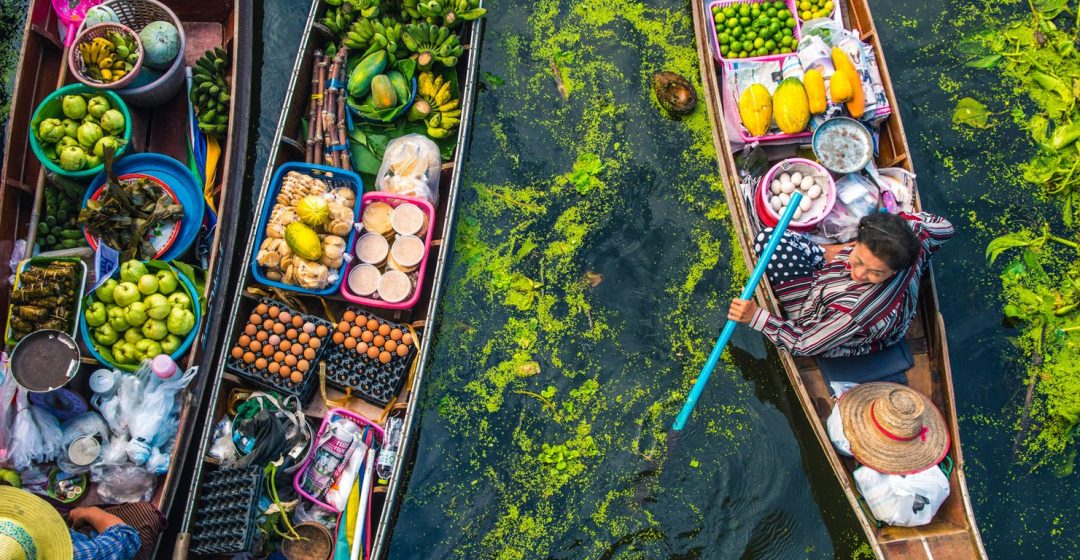 Female vendor sells food from a longtail boat at a floating market in Bangkok, Thailand