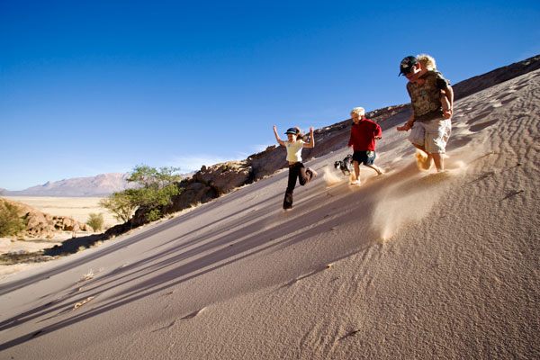 Family running down sand dunes on Brandberg Mountain, Namibia