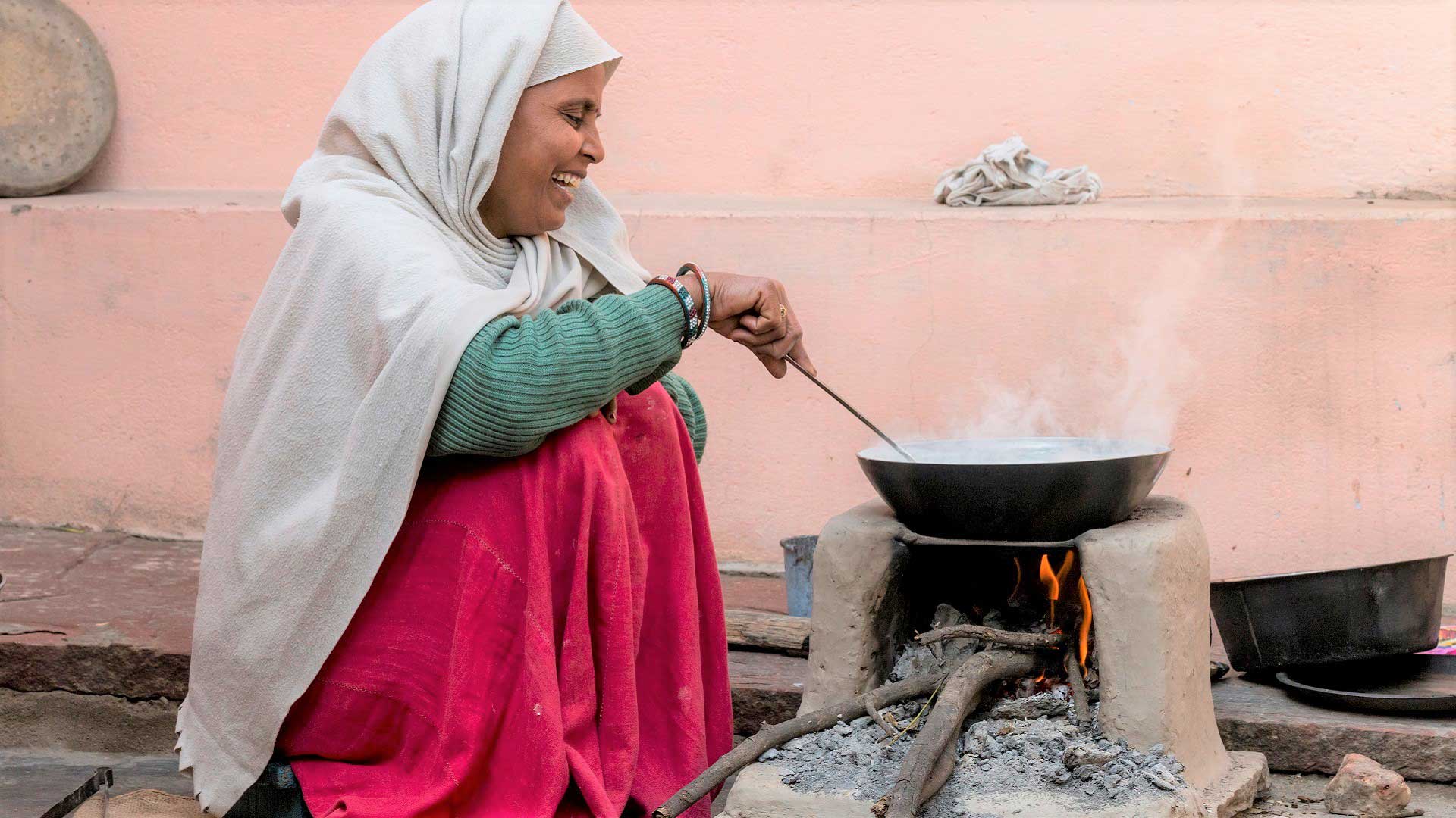 Woman joyfully cooking in Fatehpur Sikri village of Rajasthan, India with GeoEx