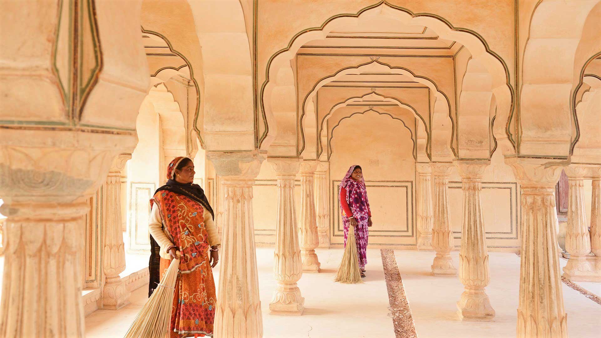 Two sari-clad women stand under elegant archways of Amer (Amber) Fort in Jaipur, India with GeoEx