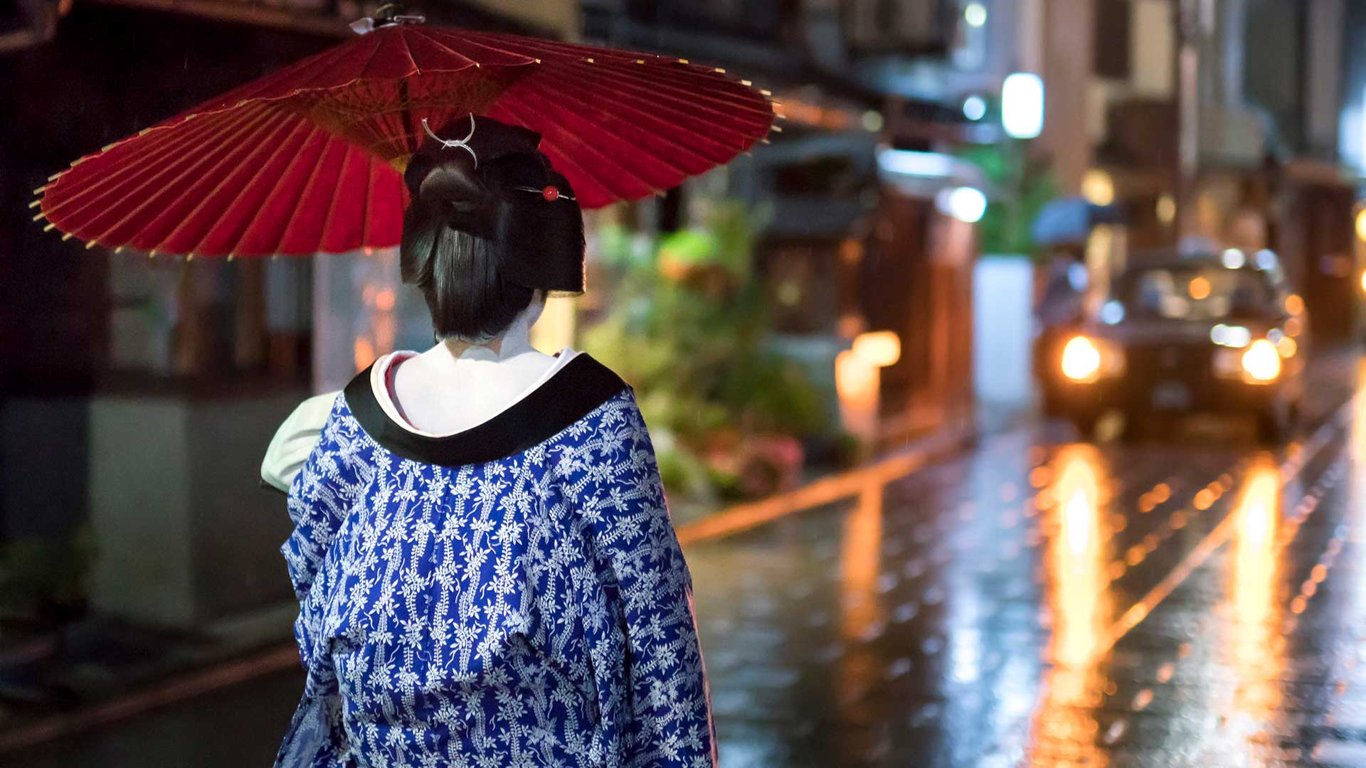 Maiko with umbrella walking along a street, Gion district, Kyoto, Japan