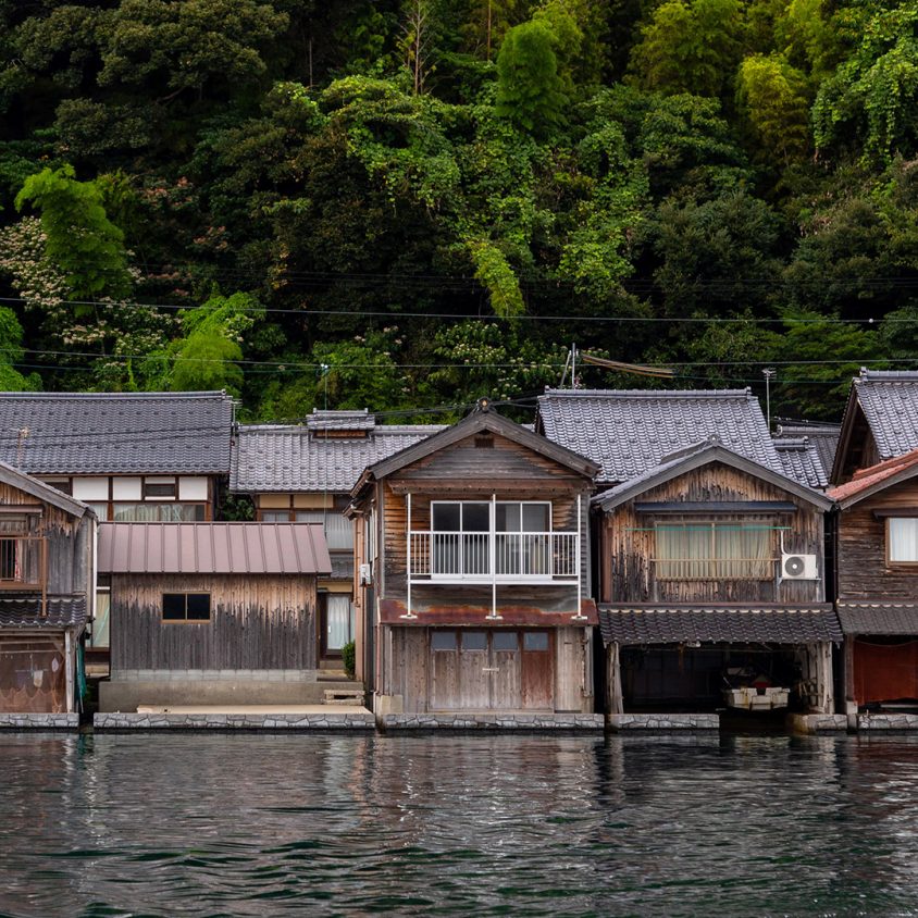 Traditional funaya residences set against lush greenery in Ine, Japan