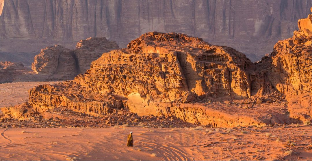 Bedouin man walking across desert, Wadi Rum, Jordan