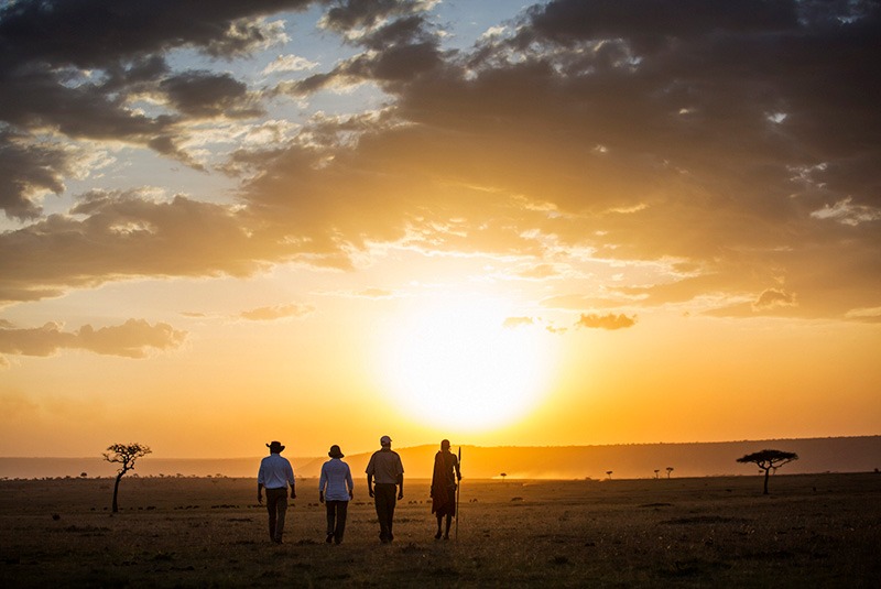 A couple on a sunset walking safari in the Masai Mara, Kenya