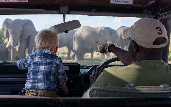 A small boy and his guide look at elephants through the windshield of their safari vehicle, Amboseli National Park, Kenya