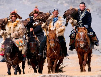 Eagle hunters riding horses to the Eagle Hunters festival in Mongolia.