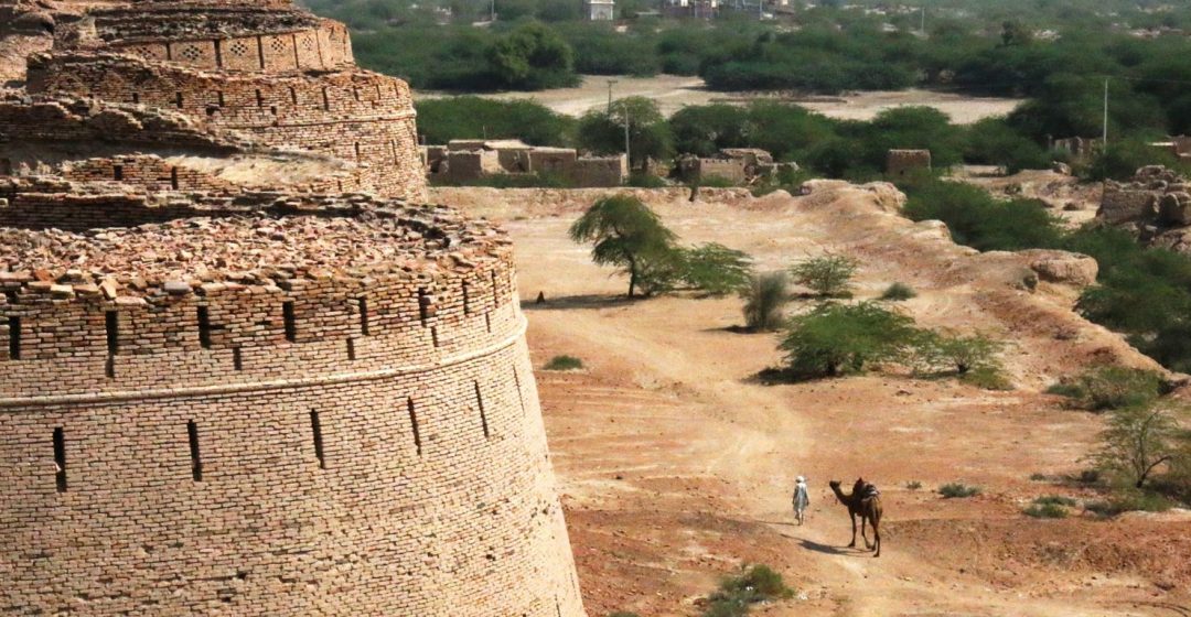 Man with camel walks outside Derawar Fort in Bahawalpur, Pakistan