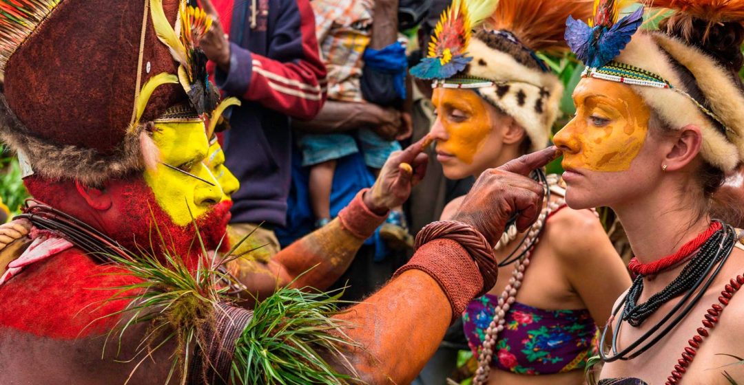 Tribesmen paint the faces of visitors during a traditional sing-sing in Papua New Guinea's Mount Hagen