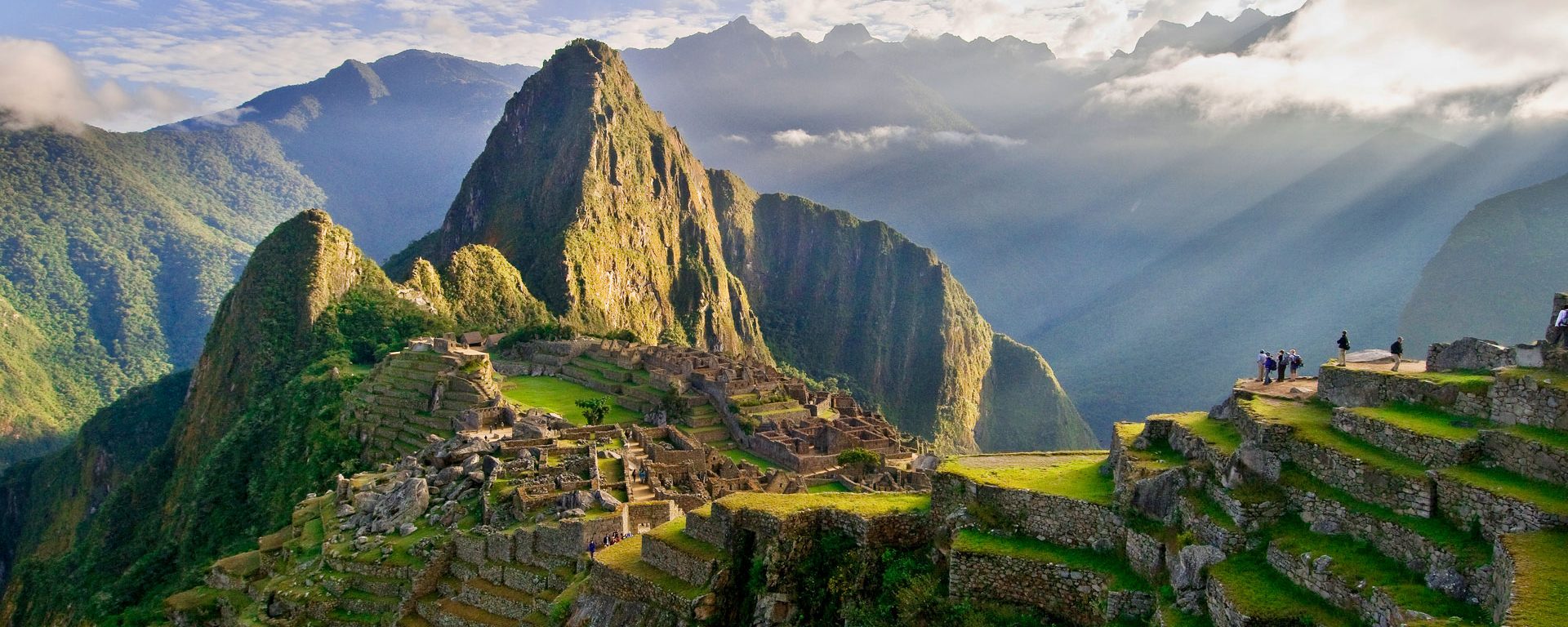 The suns rays break through the clouds illuminating Huayna Picchu, Machu Picchu, Peru