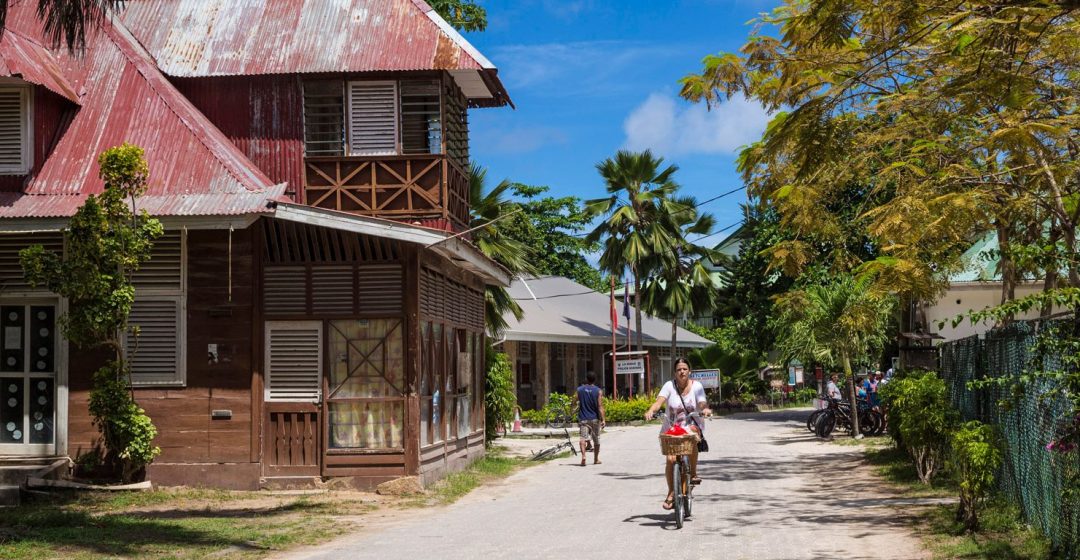 Woman rides bicycle in La Passe on La Digue Island, Seychelles