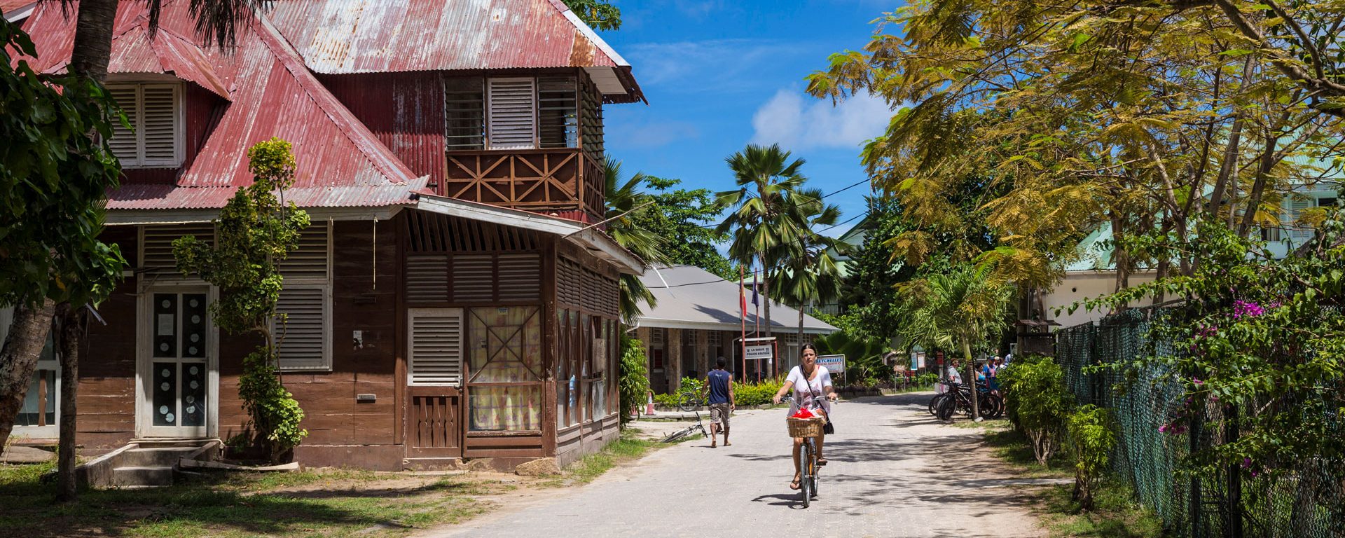 Woman rides bicycle in La Passe on La Digue Island, Seychelles