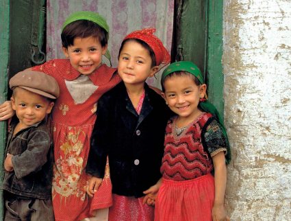 Friendly children smile from their doorway in Kashgar, China, Silk Road