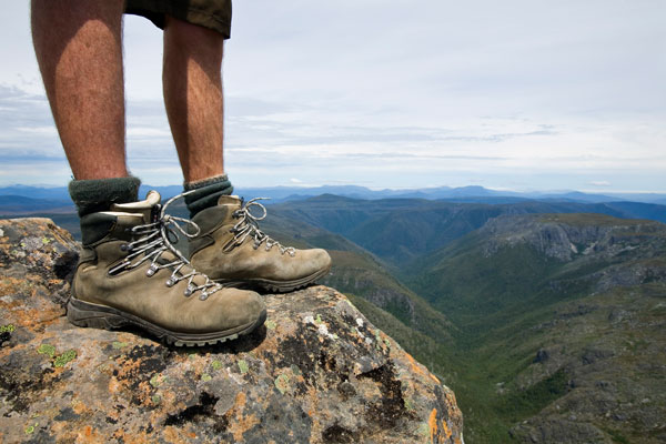 Feet-only view of hiker standing on the summit of Cradle Mountain, Tasmania, Australia